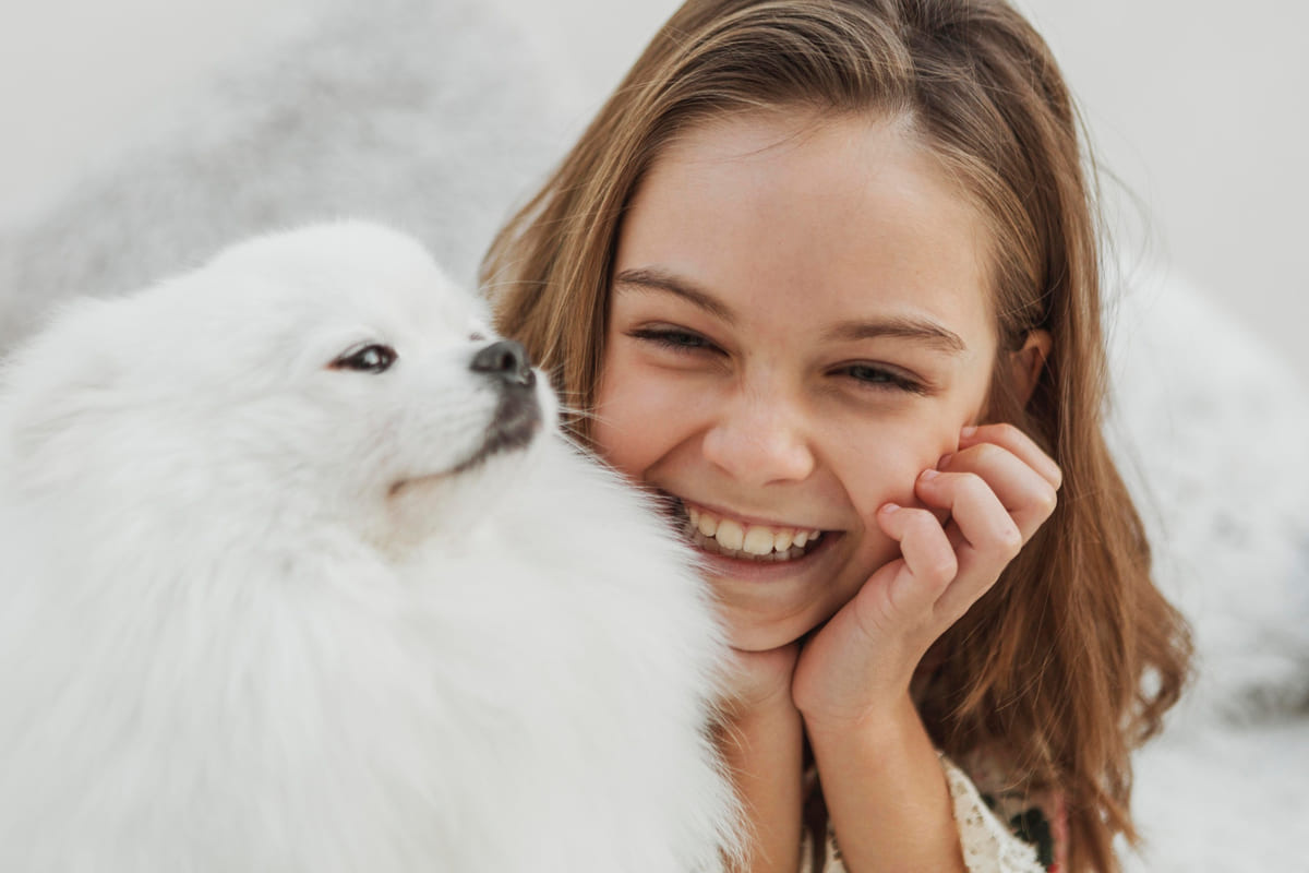 beyaz tüylü köpeğine gülümseyerek bakan küçük kız